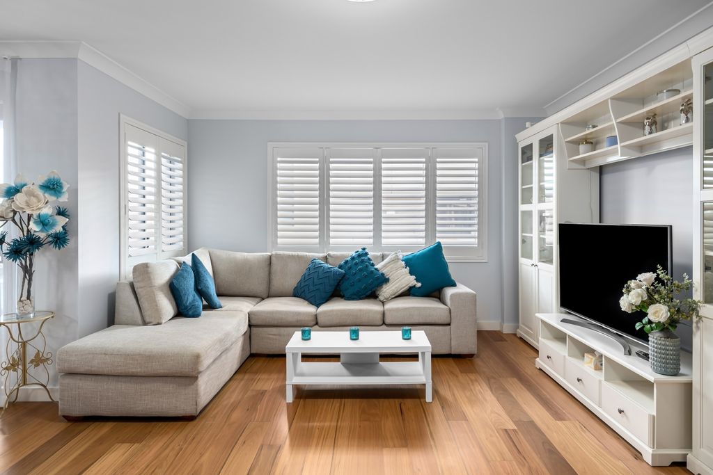 Elegant living room featuring a gray sofa, blue accents, and a flat screen TV.